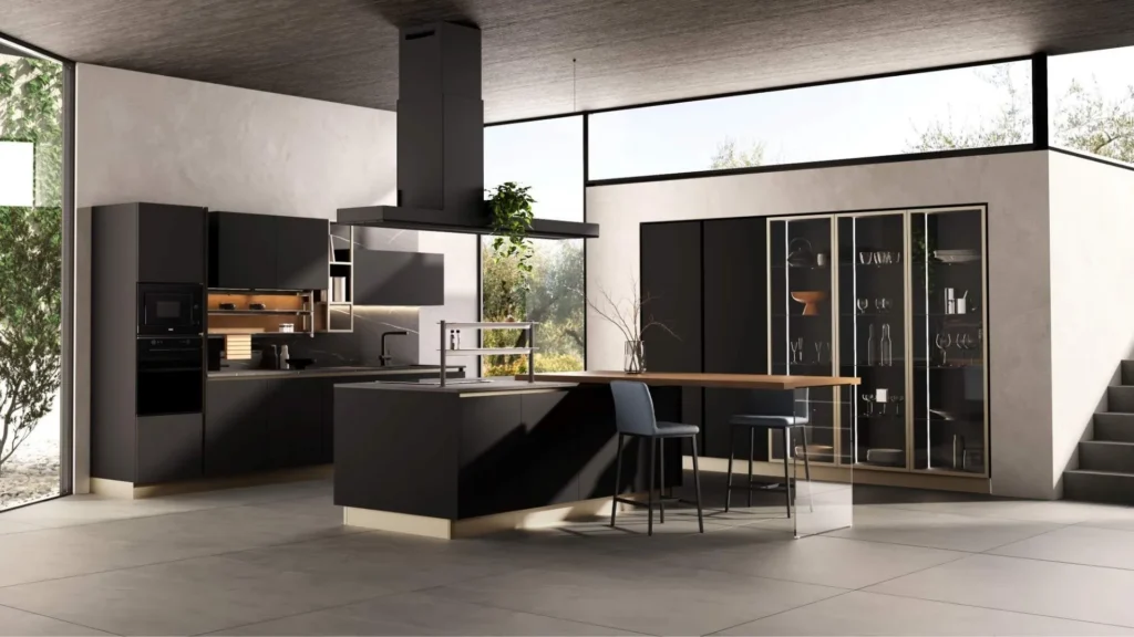 Vista interna di una moderna cucina con isola centrale. Modello Dafne Black di Behome, con piano snack in legno supportato da vetro, due sgabelli blu e una vetrina illuminata.