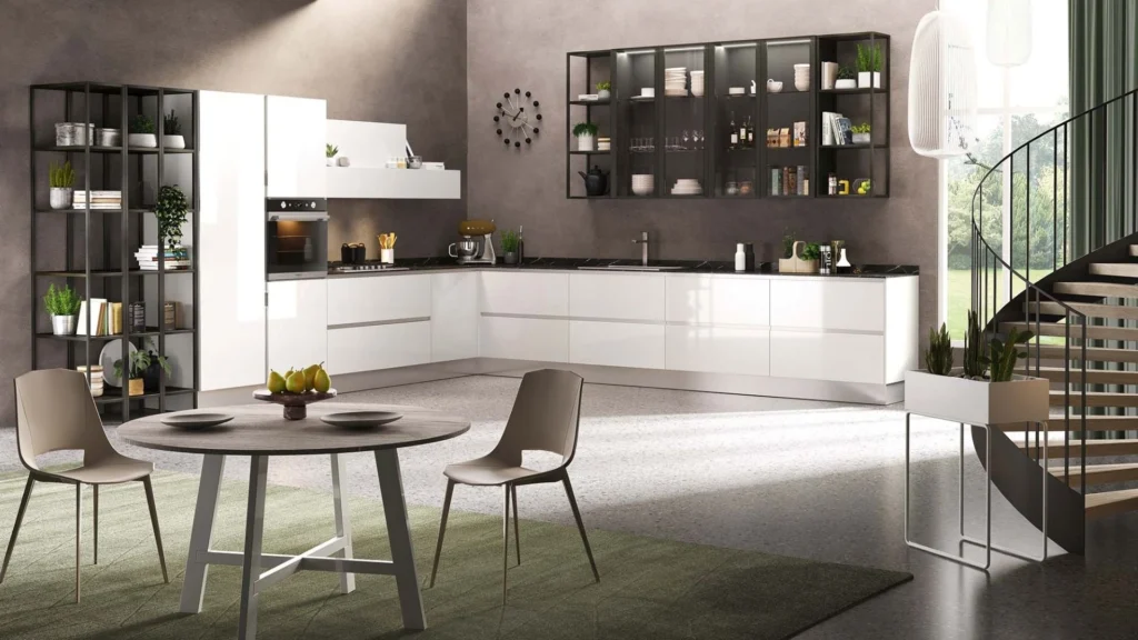 Cucina angolare Dafne Gold di BEHOME con mobili bianchi lucidi, top scuro, libreria a giorno e tavolo con sedie.