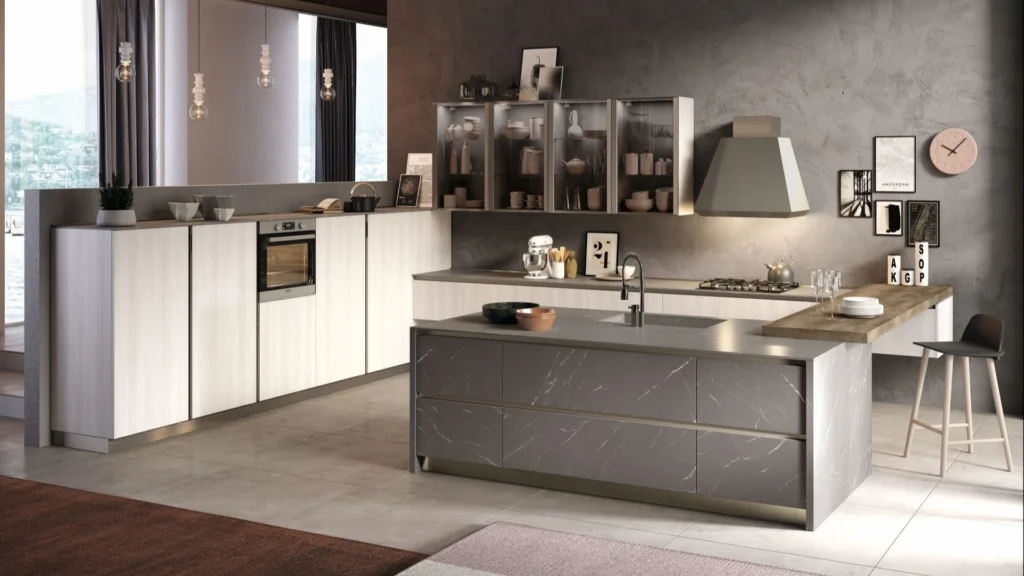 Cucina con isola Dafne In di BEHOME con mobili chiari, grande isola in marmo grigio, pensili a vetro e sgabello.
