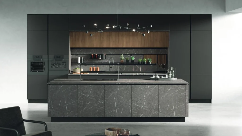 Cucina con isola Dafne Sun di BEHOME con colonne scure, dettagli in legno e grande isola centrale in marmo grigio.