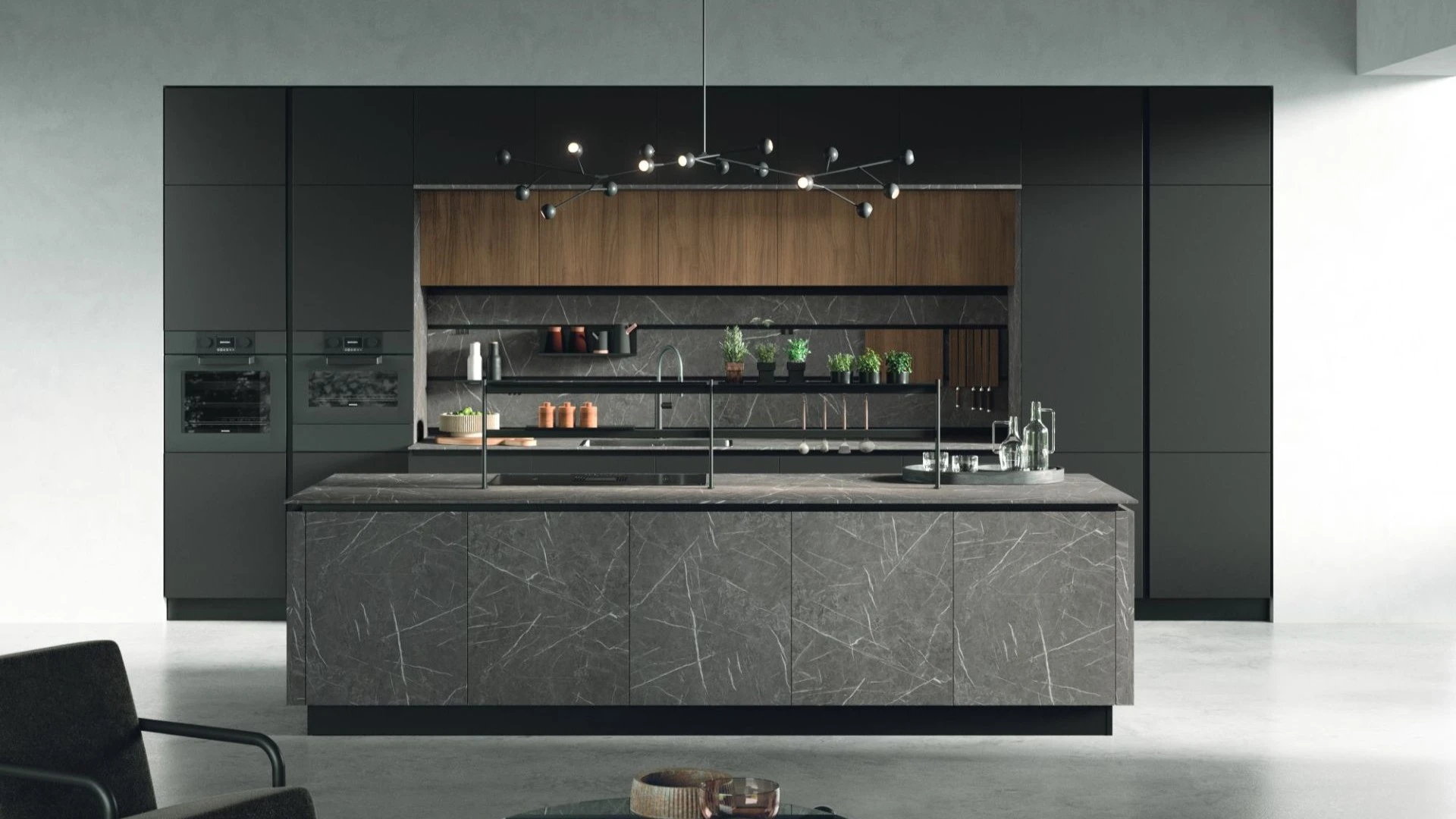 Cucina con isola Dafne Sun di BEHOME con colonne scure, dettagli in legno e grande isola centrale in marmo grigio.