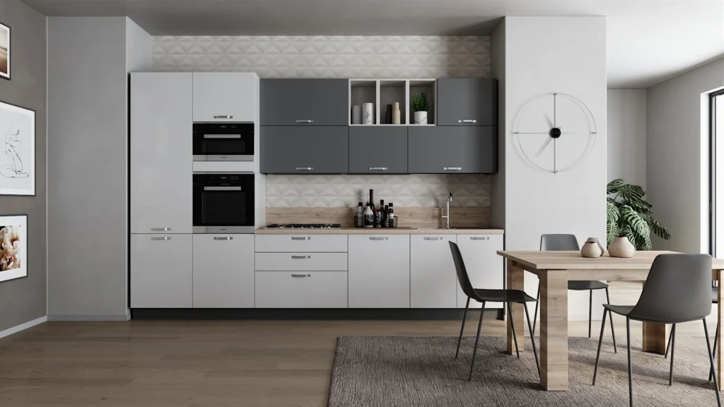 Cucina lineare Palio Smart di BEHOME con mobili bianchi e grigi, doppio forno, tavolo in legno e sedie nere.