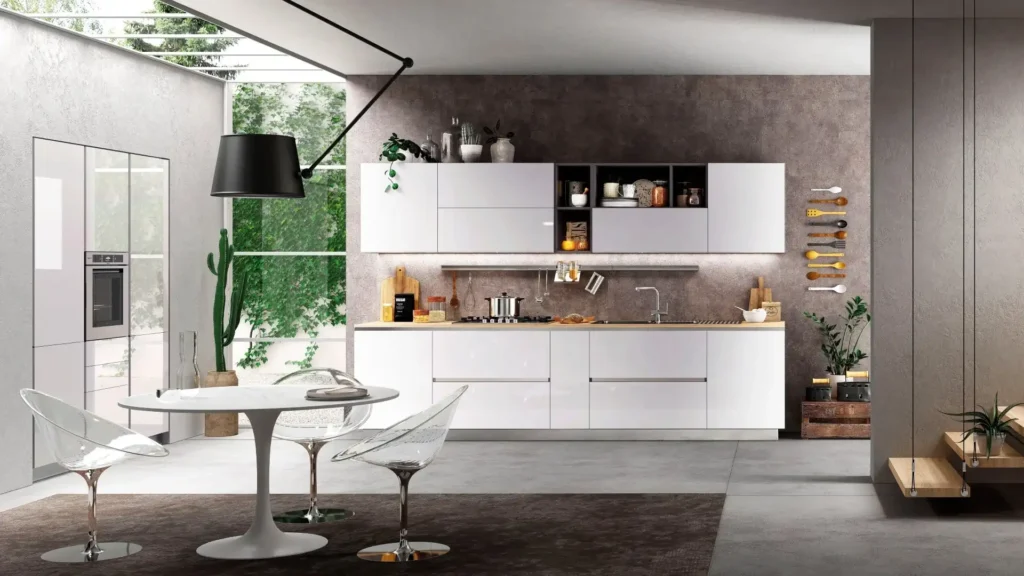 Cucina moderna Dafne Light con ante bianche lucide, top in legno, tavolo rotondo e sedie trasparenti.