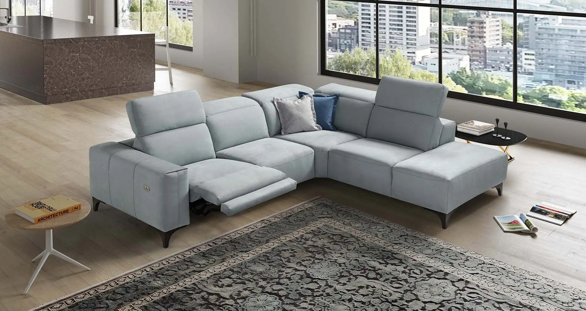 Divano angolare Marea di BEHOME azzurro con meccanismo relax aperto in un grande living.