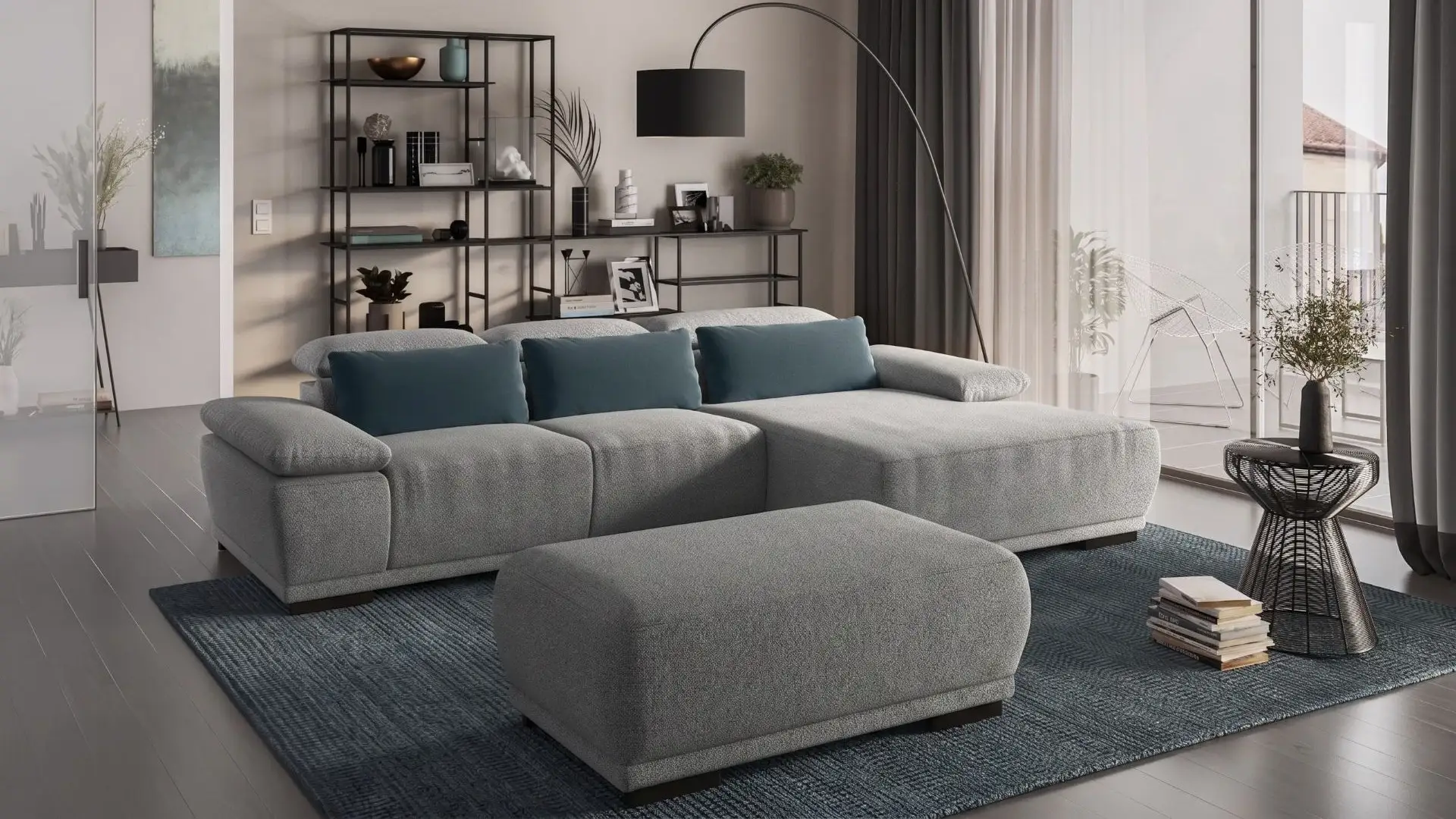 Divano con penisola Turek di BEHOME in tessuto grigio con pouf abbinato e cuscini blu.