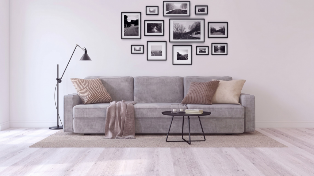 Divano a tre posti Siattle In di BEHOME grigio chiaro con cuscini decorativi e plaid.