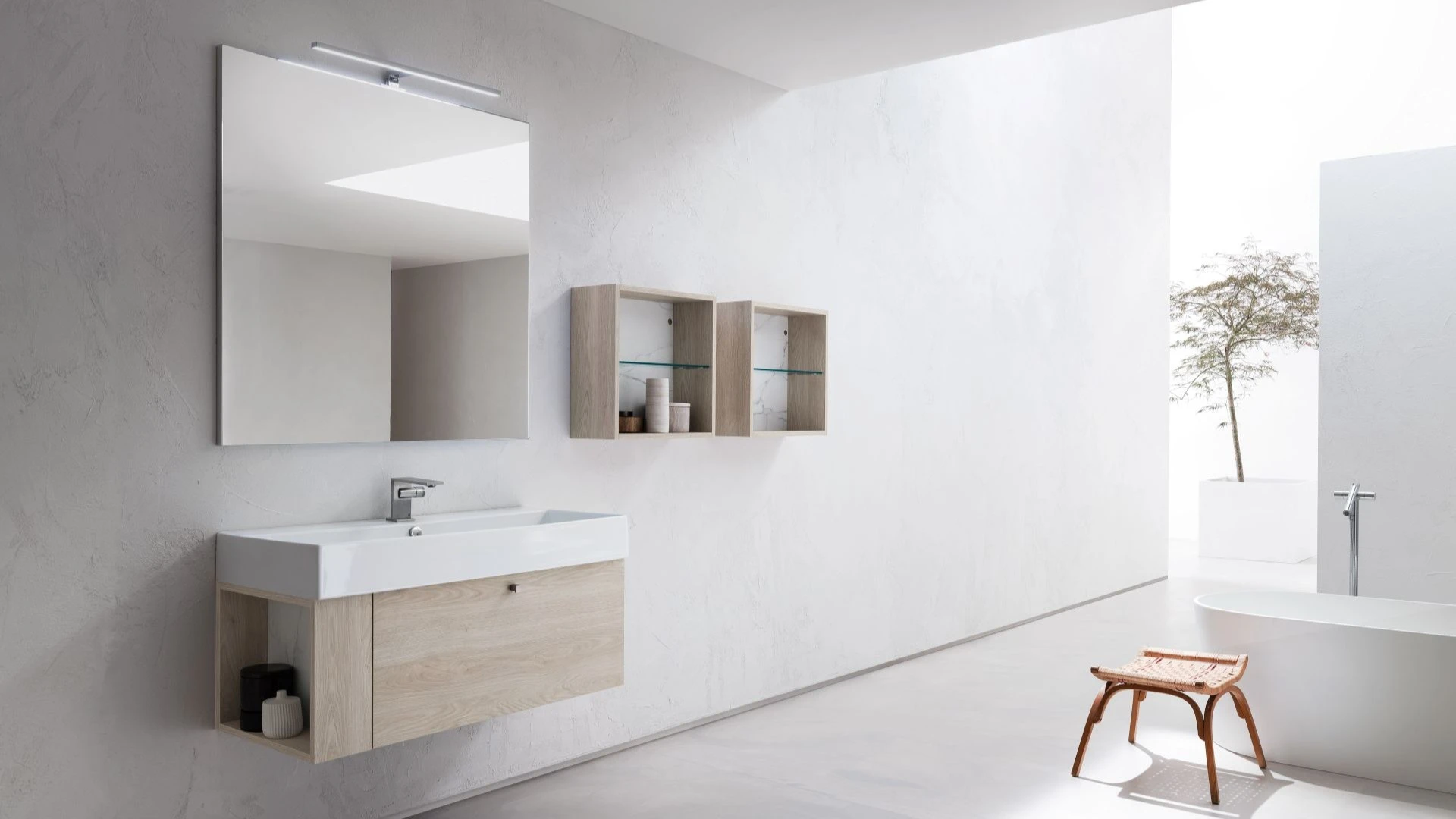 Mobile bagno sospeso Alan di BEHOME in legno chiaro in un bagno moderno e luminoso.