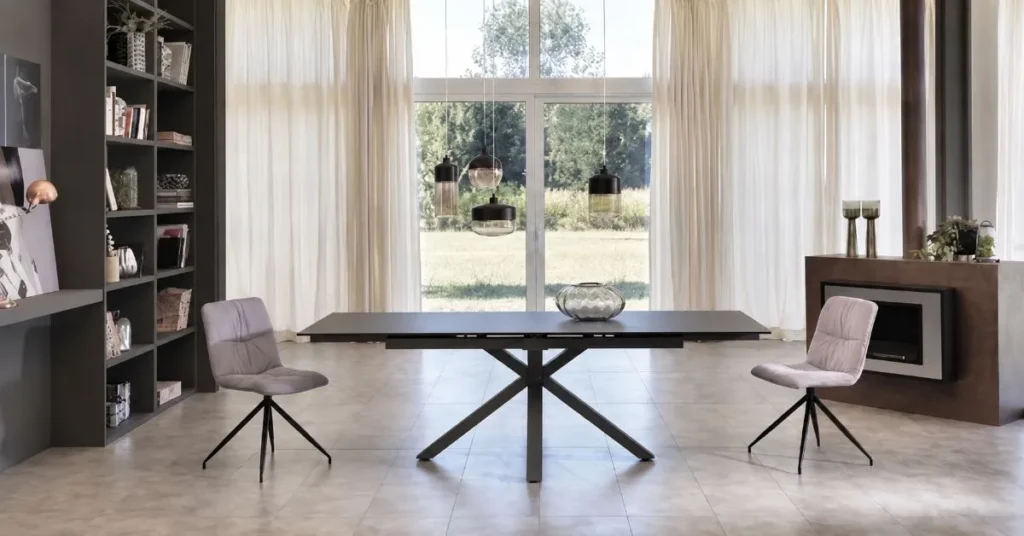 Porte finestra incorniciate da tende trasparenti color crema drappeggiate in tessuto leggero, che massimizzano l'illuminazione naturale e la vista sul giardino esterno