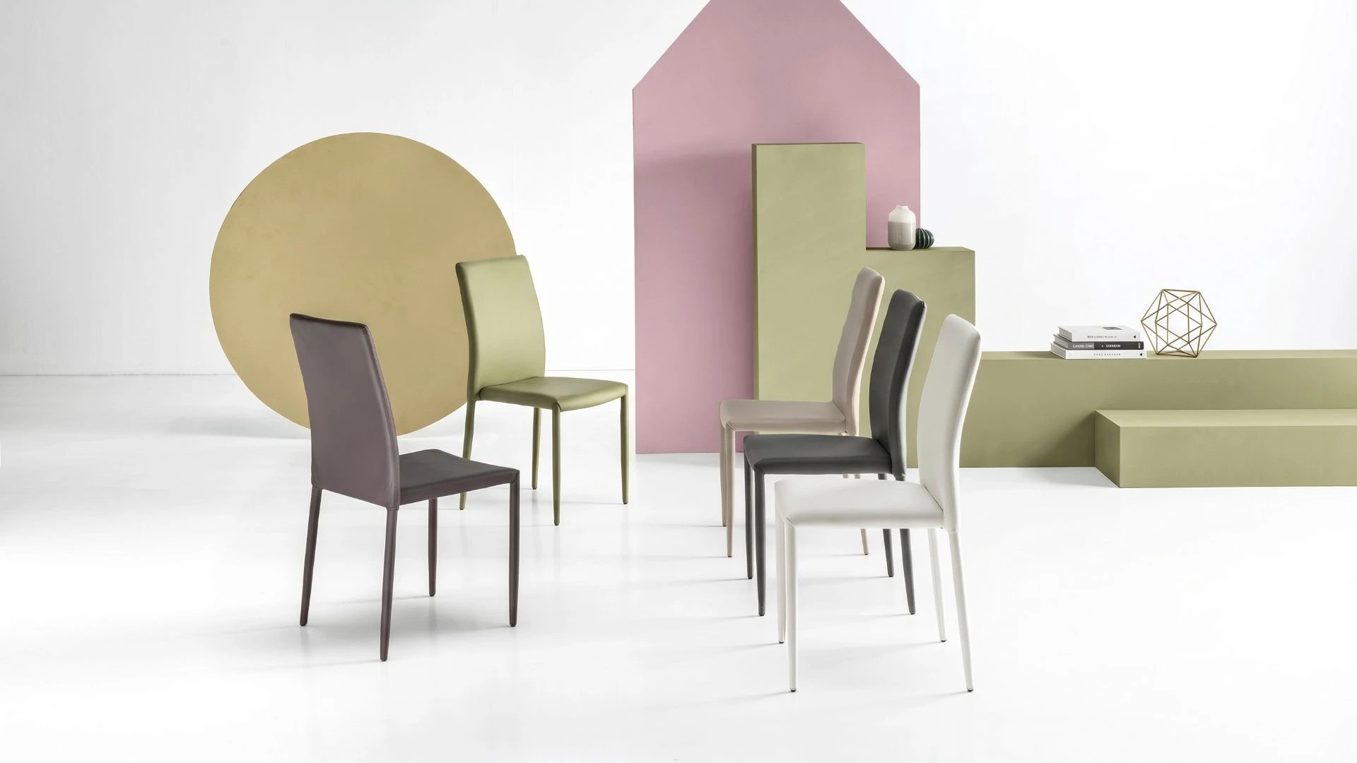 Gruppo di sedie in ecopelle Manila BEHOME di vari colori in un ambiente moderno.